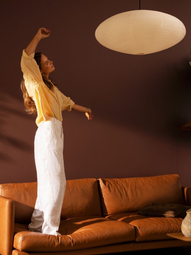woman dancing in cosy living room with warm brown colour wall and sofa