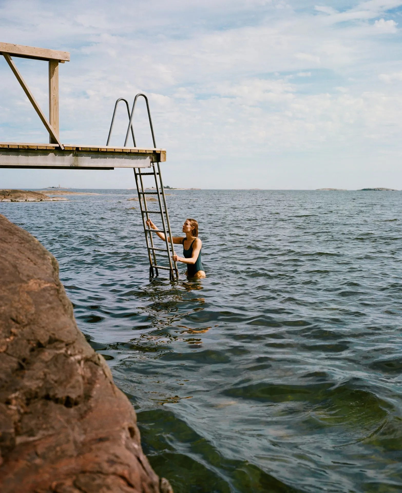 woman swimming in sea near rocky beach